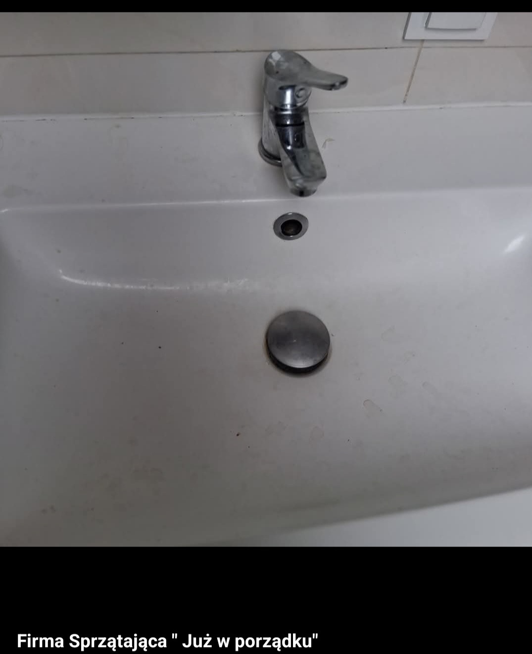 Biała, zabrudzona umywalka z chromowaną baterią i odpływem, widoczne ślady po wodzie i zabrudzenia na powierzchni.