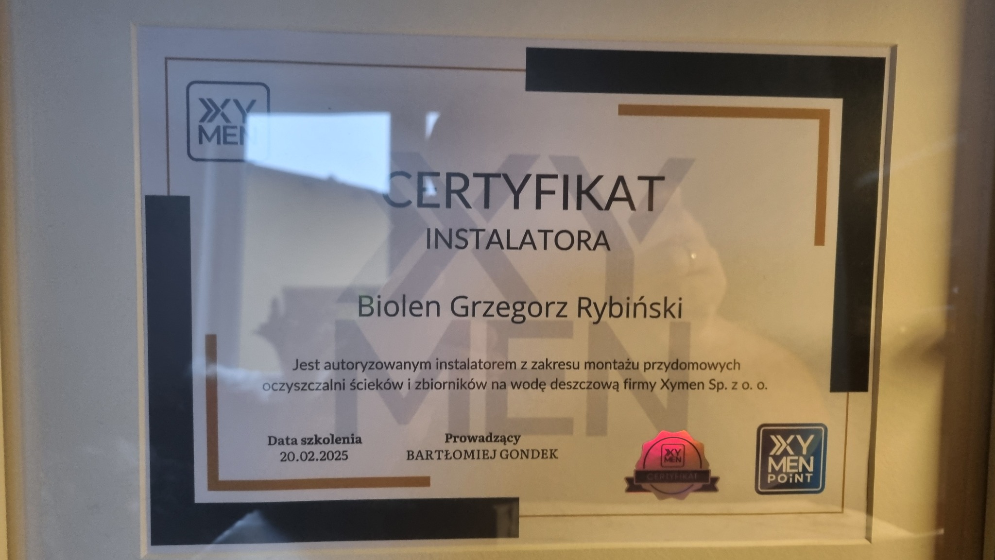 Oprawiony w ramkę certyfikat instalatora przydomowych oczyszczalni ścieków i zbiorników na wodę deszczową firmy Xymen Sp. z o.o. dla Biolena Grzegorza Rybińskiego, z datą szkolenia 20.02.2025.