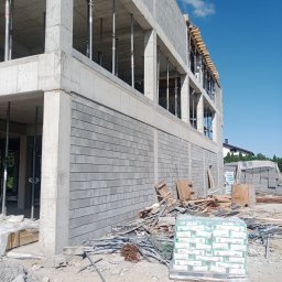 OM-GOR OLEH HORBYK - Wznoszony budynek z betonu komórkowego, widoczne podpory stropu, materiały budowlane na placu budowy, błękitne niebo w tle.