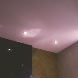 Marcin Wołoszyn - Nowoczesna łazienka z oświetleniem punktowym w suficie, ciemną ścianą i płytkami ułożonymi w jodełkę, widok na okno.