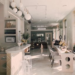 Wykończenia-warszawa - Jasne, przestronne wnętrze salonu kosmetycznego z marmurową podłogą, białymi ścianami z dekoracyjnymi listwami, wiszącymi lampami w kształcie kul, stanowiskami do manicure z lampkami w stylu art...