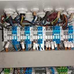 KJ-ster Elektro-serwis - Rozdzielnica elektryczna wewnątrz szafy sterowniczej z podłączonymi przewodami i oznaczonymi złączkami, widoczne numery X91-X95. Detal instalacji elektrycznej.