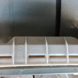 Wnętrze urządzenia AGD z widocznym, białym elementem z tworzywa sztucznego oznaczonym numerem A03459401 i widocznymi przewodami elektrycznymi.