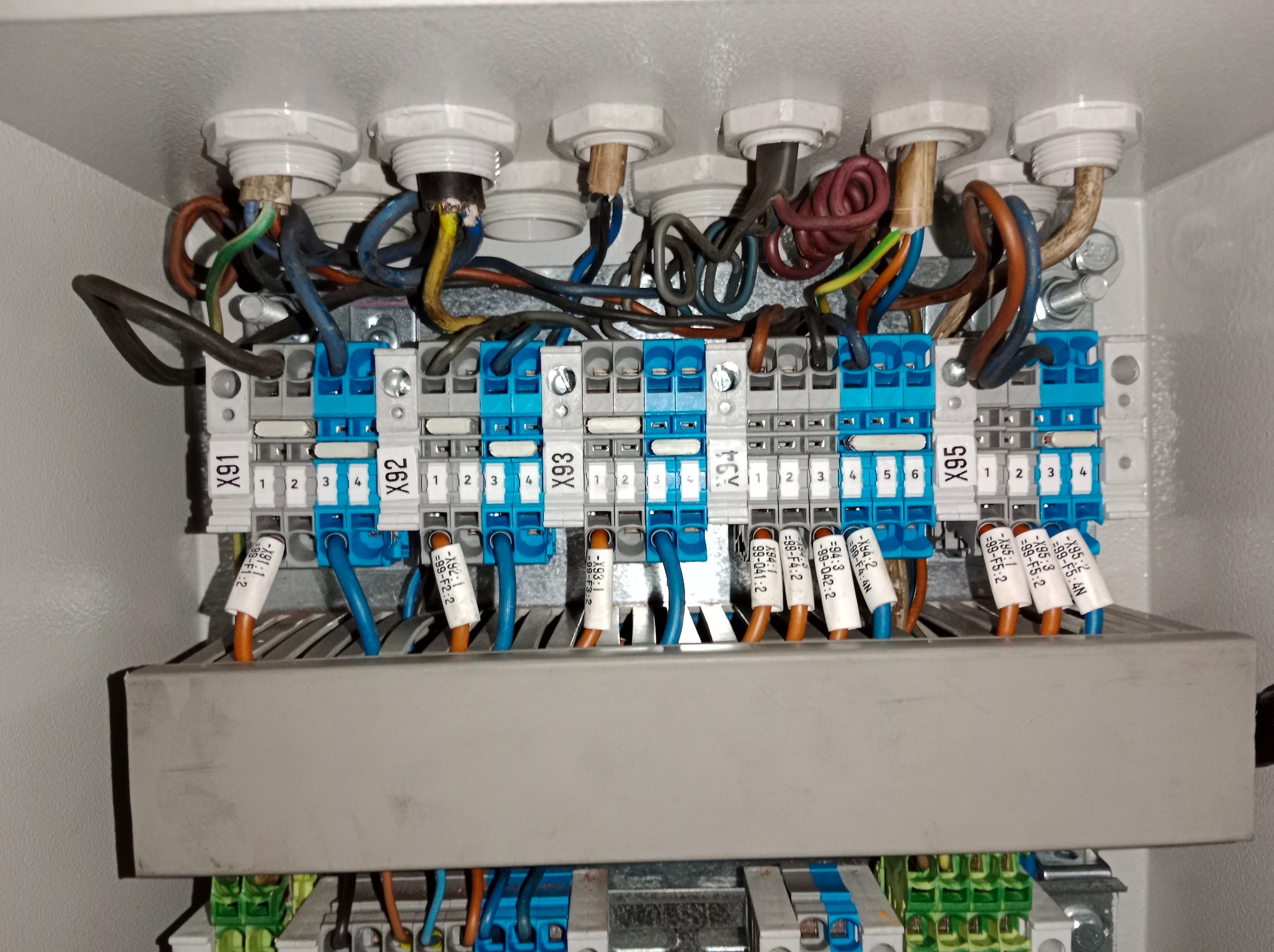 Rozdzielnica elektryczna wewnątrz szafy sterowniczej z podłączonymi przewodami i oznaczonymi złączkami, widoczne numery X91-X95. Detal instalacji elektrycznej.