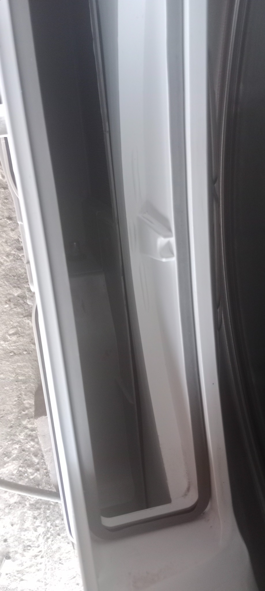 Wnętrze pralki automatycznej z widoczną uszczelką drzwi i elementami obudowy. Detal przedstawia stan techniczny przed ewentualną naprawą lub wymianą.