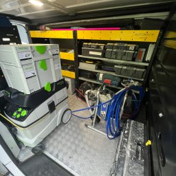 Mirosław Nieśpiał Mr Handy - Wnętrze samochodu dostawczego z narzędziami i sprzętem malarskim, w tym agregat malarski Graco i odkurzacz Festool z pojemnikami, uporządkowane na półkach Autorack.