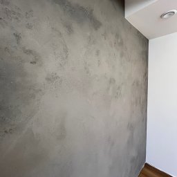 Mirosław Nieśpiał Mr Handy - Ściana z efektem dekoracyjnym w odcieniach szarości, wykonana w Józefowie, z widocznym fragmentem białego sufitu i podłogi z paneli.