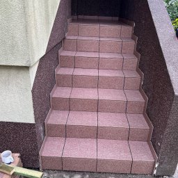 Mirosław Nieśpiał Mr Handy - Wyłożone płytkami schody wejściowe do budynku, widoczne niedokończone prace, obok leży kubek i resztki materiałów budowlanych.