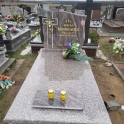 Granitowy nagrobek z wyrytym imieniem i nazwiskiem Janina Kondracka, datą urodzenia i śmierci, ozdobiony krzyżem z Jezusem i kwiatami, z dwoma zapalonymi zniczami na płycie, na cmentarzu z innymi...
