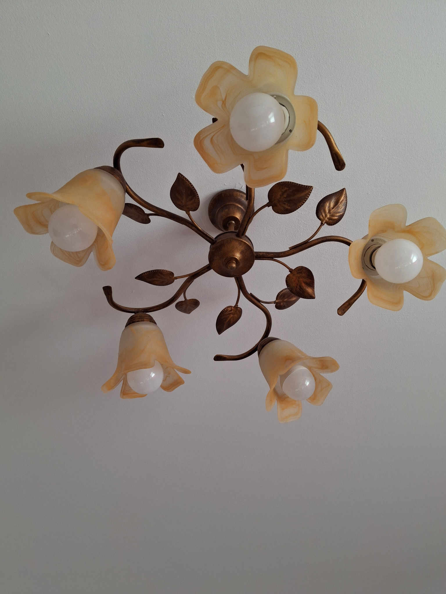 Żyrandol sufitowy z pięcioma kloszami w kształcie kwiatów w odcieniach beżu i złota, umieszczony na białym suficie.