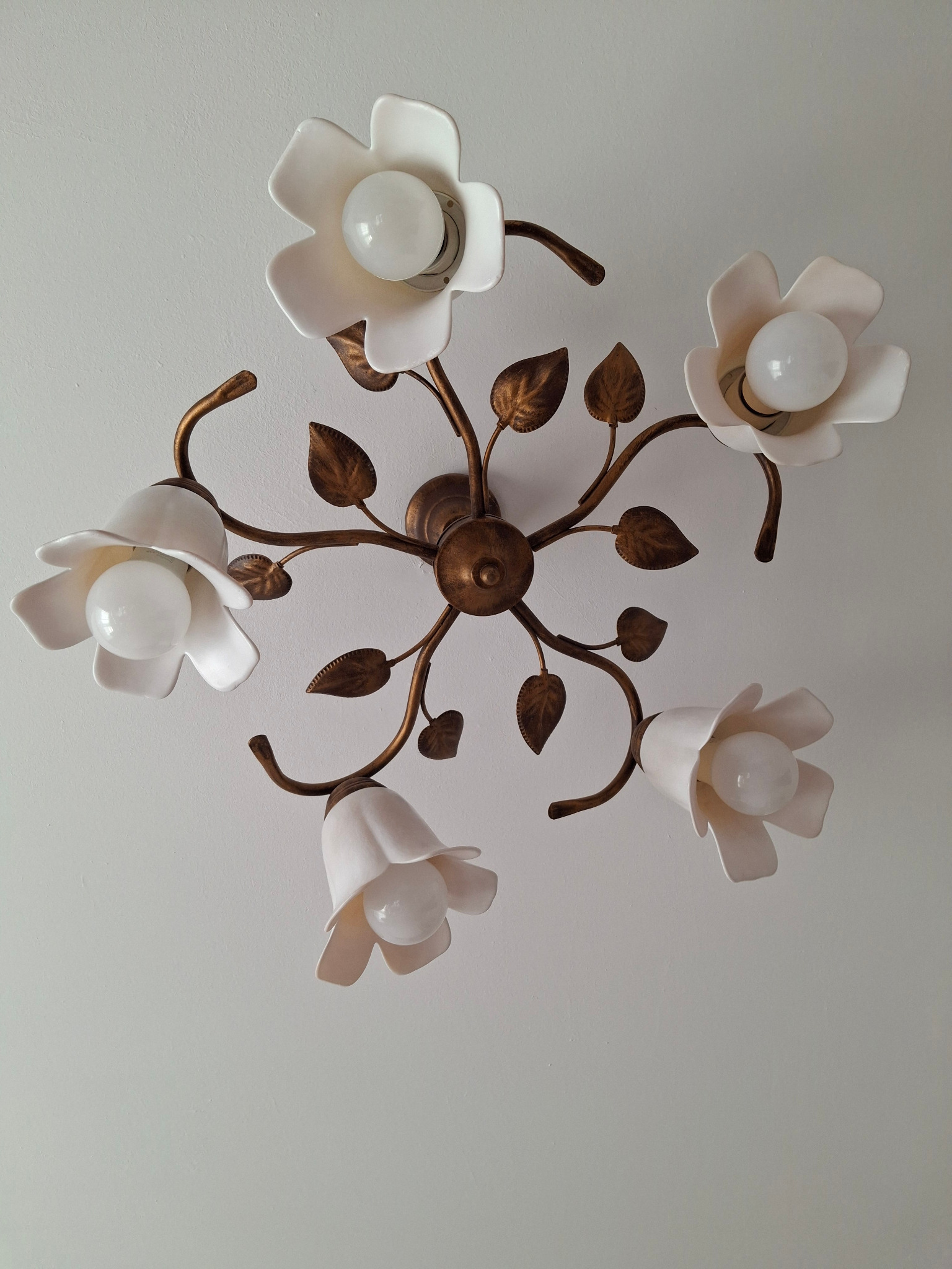Dekoracyjna lampa sufitowa z białymi kloszami w kształcie kwiatów i metalowymi, brązowymi elementami przypominającymi liście.