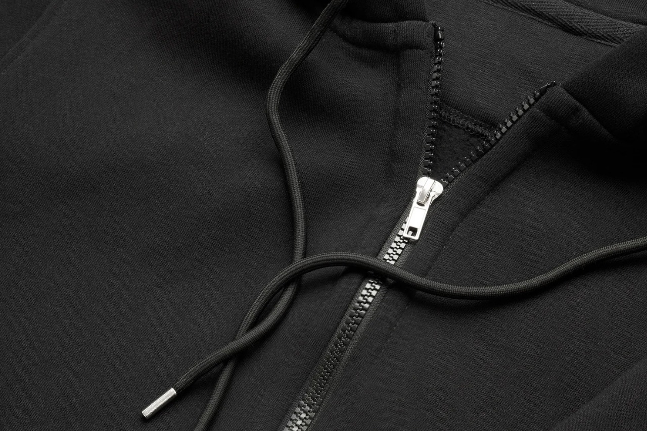 Czarne rozpinane hoodie z metalowym zamkiem błyskawicznym i sznurkami z metalowymi końcówkami, widoczne z bliska