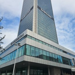 AP-TECH BUDOWNICTWO - Wysoki biurowiec z napisem SAMSUNG na tle błękitnego nieba. Budynek Presidential z nowoczesną architekturą i szklaną fasadą. Widok z dołu, podkreślający monumentalność.