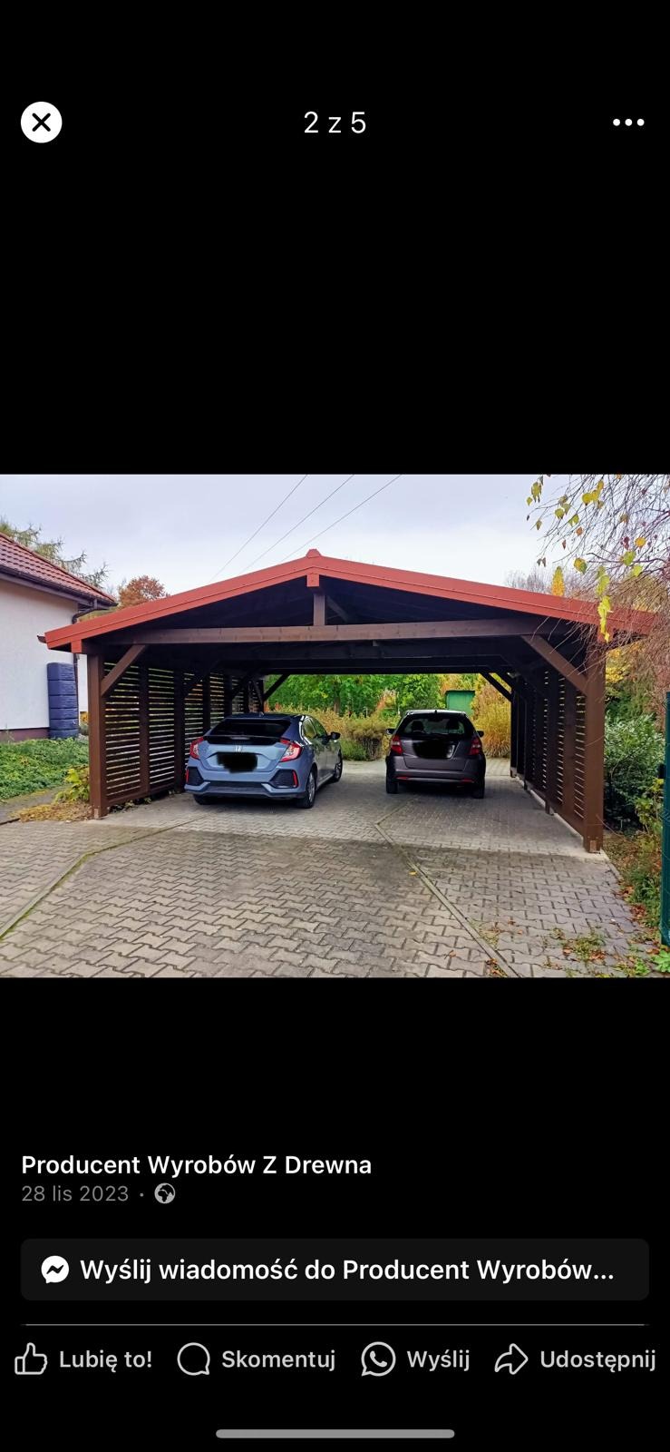 Drewniana wiata garażowa w kolorze ciemnego brązu z czerwonym dachem kryjąca dwa samochody na brukowanym podjeździe.