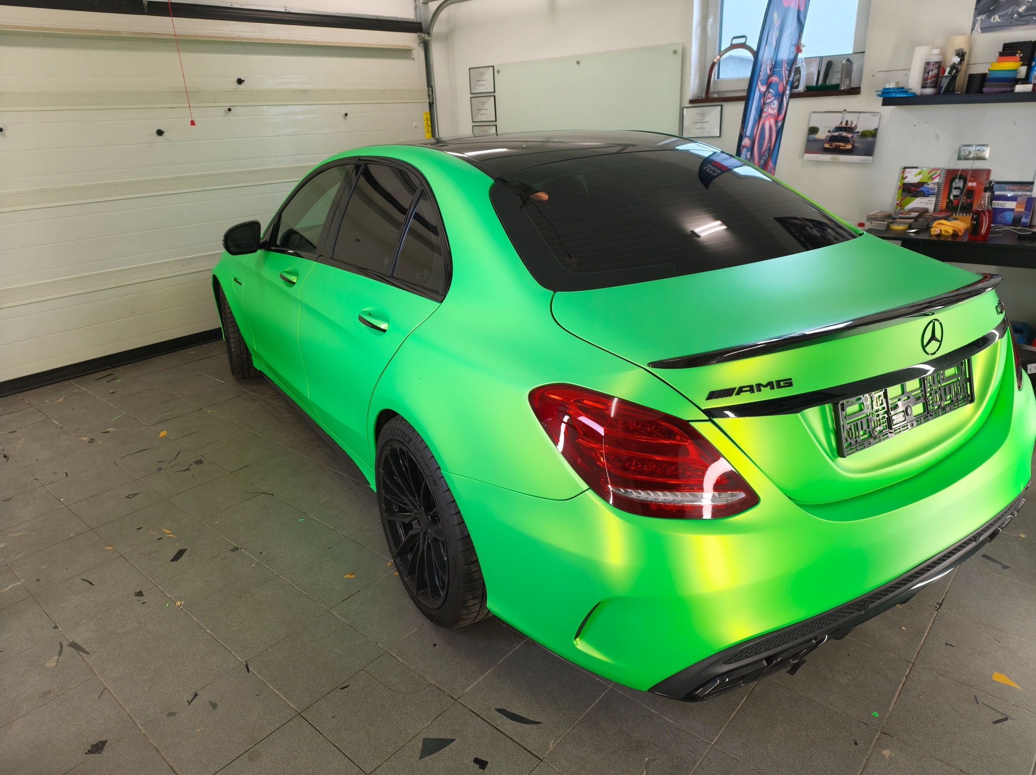 Jaskrawo zielony Mercedes AMG po oklejeniu folią, widok z tyłu w warsztacie. Matowa zieleń kontrastuje z czarnymi felgami i dachem.