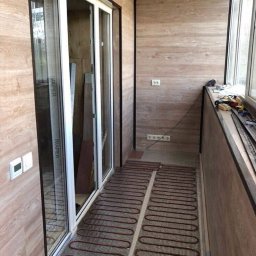 Builder - Balkon z panelami ściennymi imitującymi drewno i systemem ogrzewania podłogowego w postaci mat grzewczych przed montażem wylewki.