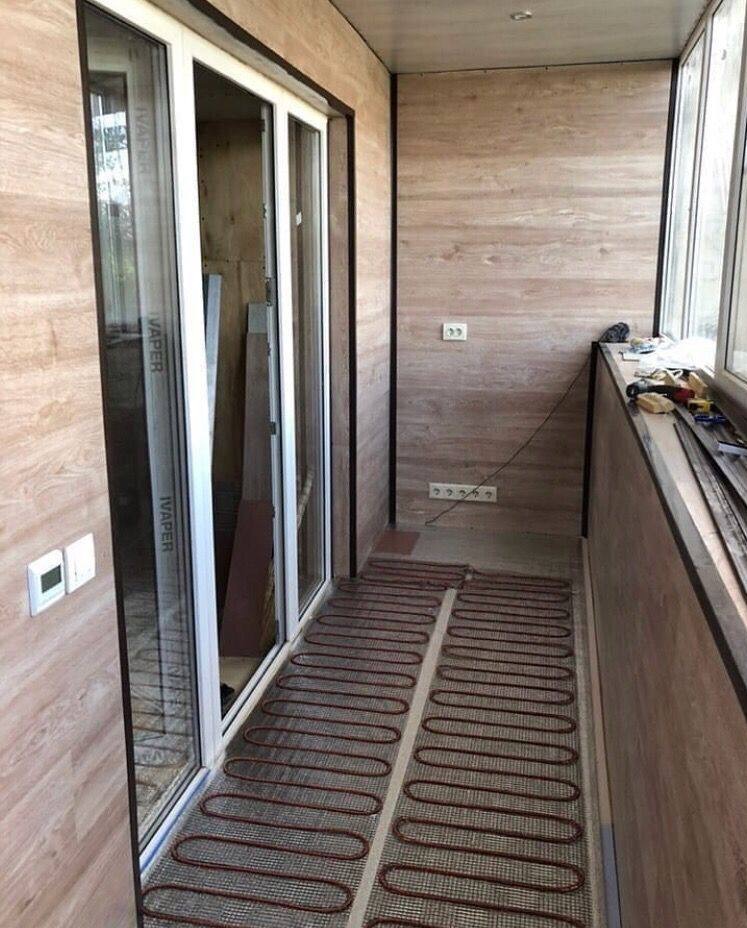 Balkon z panelami ściennymi imitującymi drewno i systemem ogrzewania podłogowego w postaci mat grzewczych przed montażem wylewki.