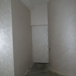 HORIZON VITALII VDOVYCHENKO - Wykończone wnętrze z dekoracyjną, jasną ścianą o strukturze przypominającej stiuk wenecki, białe drzwi. Minimalistyczny design z subtelnym połyskiem.