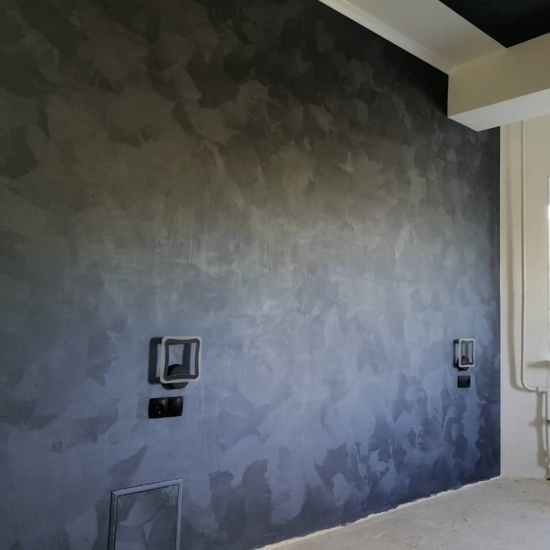 Dekoracyjna, szara ściana z efektem cieniowania i widocznymi włącznikami światła. Wykończenie wnętrza w nowoczesnym stylu z elementami surowego betonu.