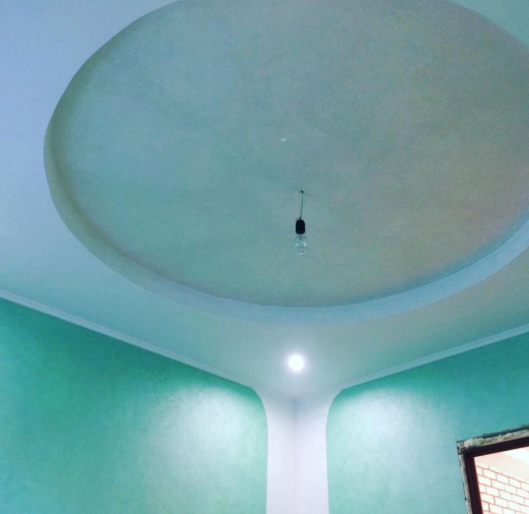 Wykończone wnętrze w Częstochowie: okrągłe podwieszane sufity z oświetleniem i pomalowane ściany w odcieniach zieleni. Widoczne detale wykończeniowe.