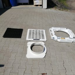 Bartosz Kijas - Rozłożone elementy klimatyzacji Kaisa na brukowanej powierzchni. Widoczny filtr, kratka, obudowa. Przygotowanie do montażu lub czyszczenia.