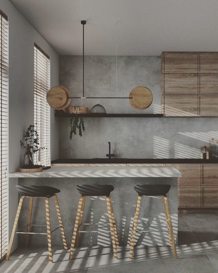 Minimalistyczna kuchnia z drewnianymi szafkami, betonową ścianą i trzema hokerami pod blatem, oświetlona lampą z drewnianymi akcentami. Żaluzje rzucają cienie na podłogę.