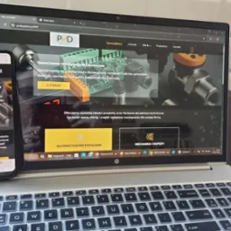 Laptop i smartfon wyświetlają stronę internetową pmdsystems.pl z elementami automatyki przemysłowej. Widoczny interfejs strony, menu i treść oferty firmy.
