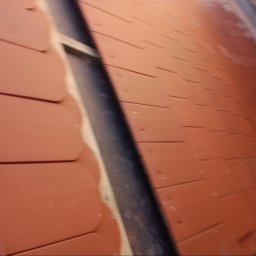 Dekarstwo Blacharstwo Sebastian Karliński JDG - Nowe, pomarańczowe dachówki karpiówki ułożone na dachu, widok z bliska, ukazuje detale montażu.