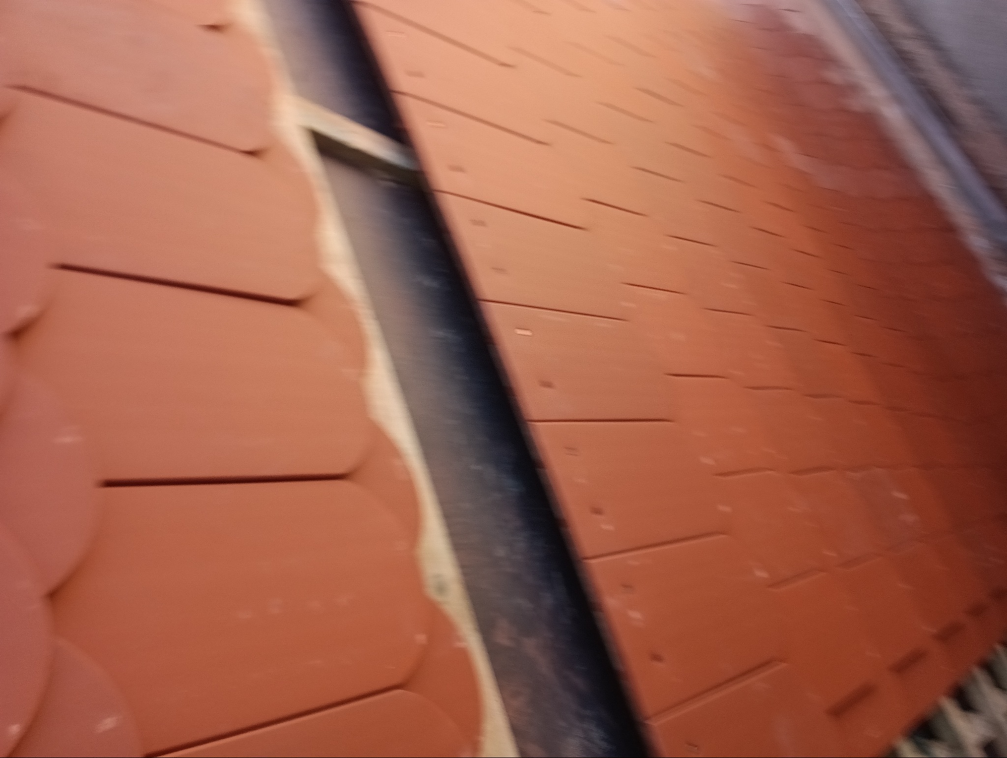 Nowe, pomarańczowe dachówki karpiówki ułożone na dachu, widok z bliska, ukazuje detale montażu.