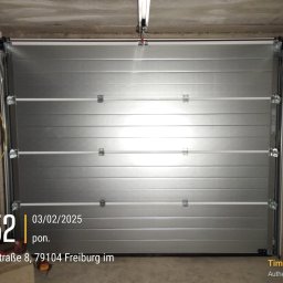 El Toro - Zamknięta, segmentowa konstrukcja garażowa w kolorze srebrnym, widoczna z wnętrza garażu, z widocznymi elementami mocującymi i prowadnicami pod sufitem.