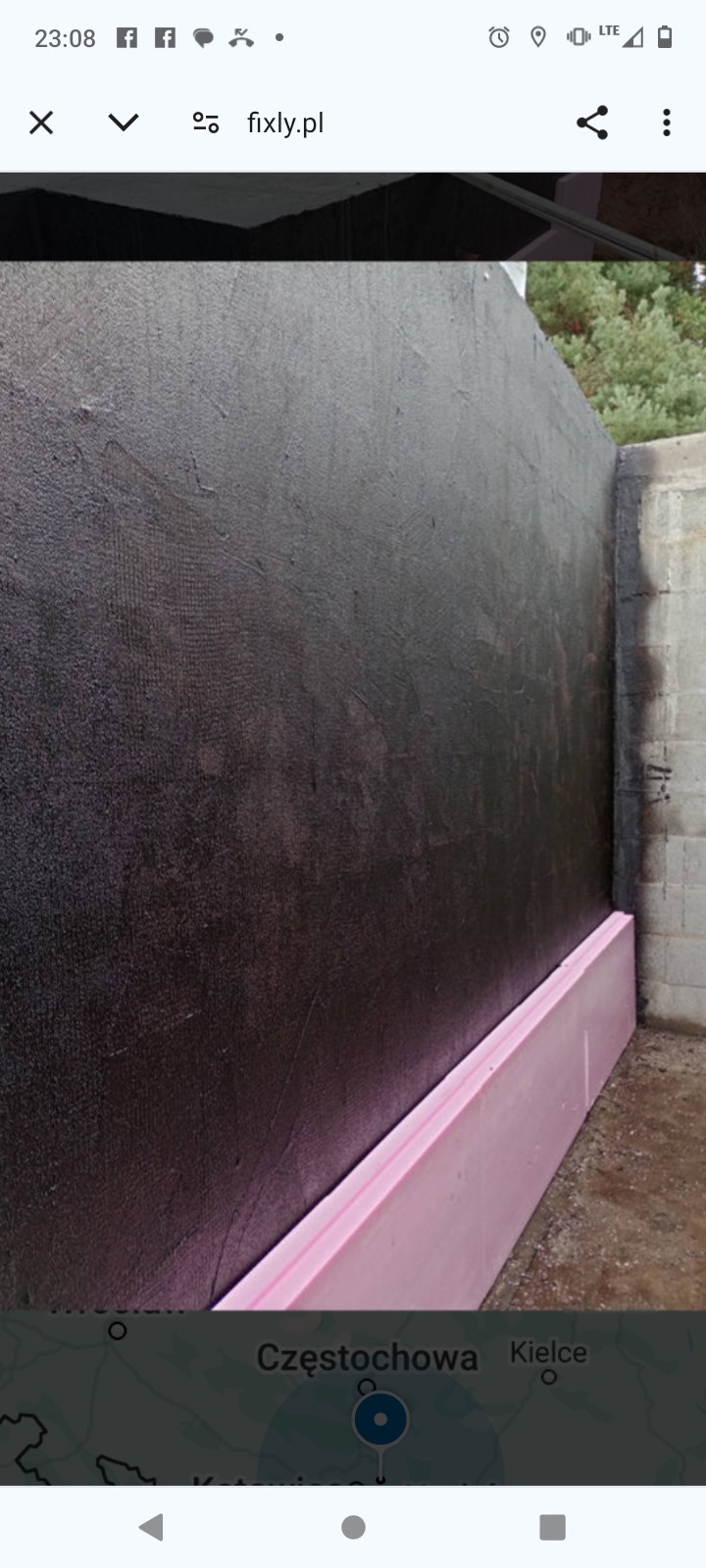 Ściana fundamentowa zabezpieczona czarną powłoką izolacyjną z widoczną różową płytą styropianową u podstawy.