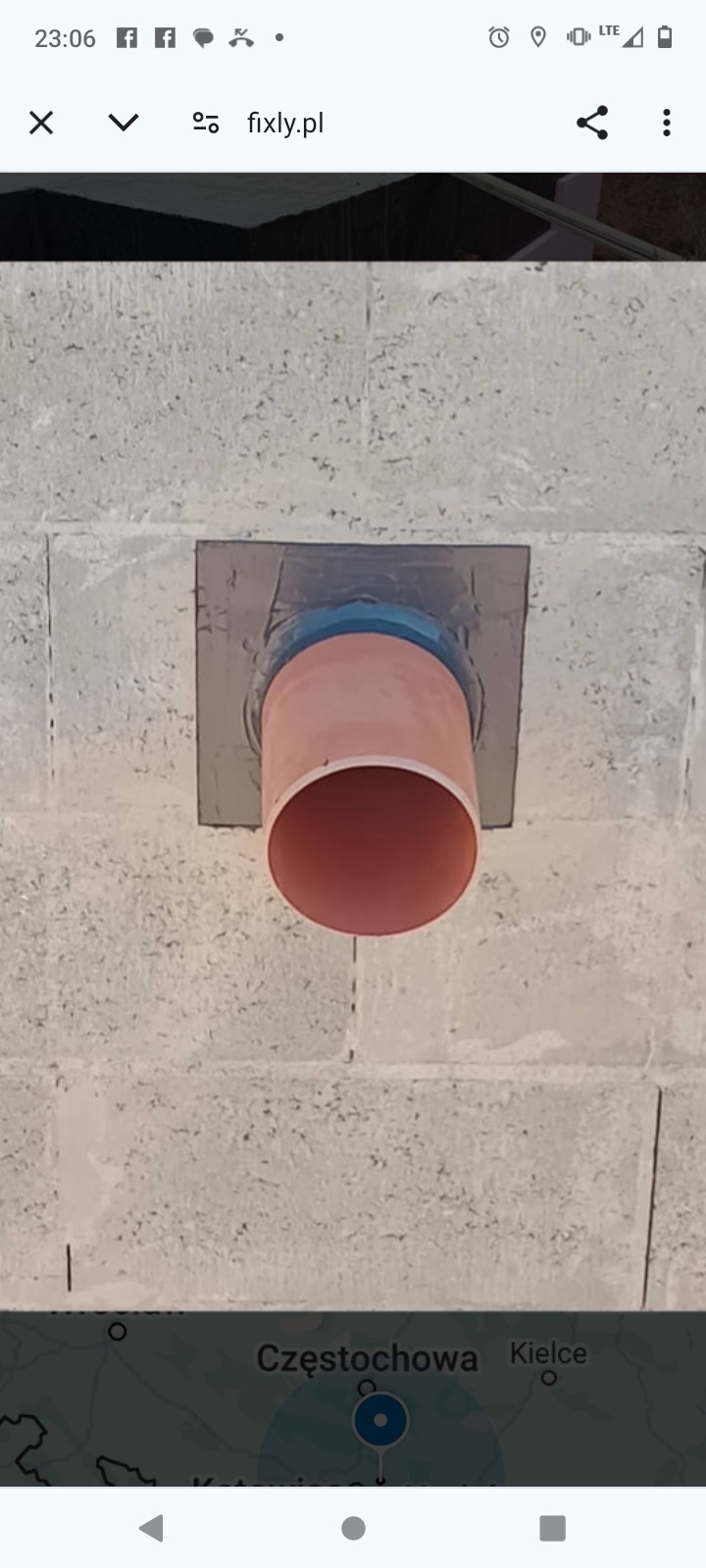 Pomarańczowa rura kanalizacyjna przechodząca przez ścianę fundamentową z szarego betonu komórkowego, uszczelniona szarą taśmą i niebieskim pierścieniem.