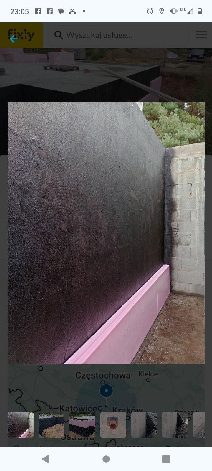 Zabezpieczona czarną powłoką i różowym styropianem ściana fundamentowa w trakcie izolacji, widoczne bloczki betonowe narożnika.