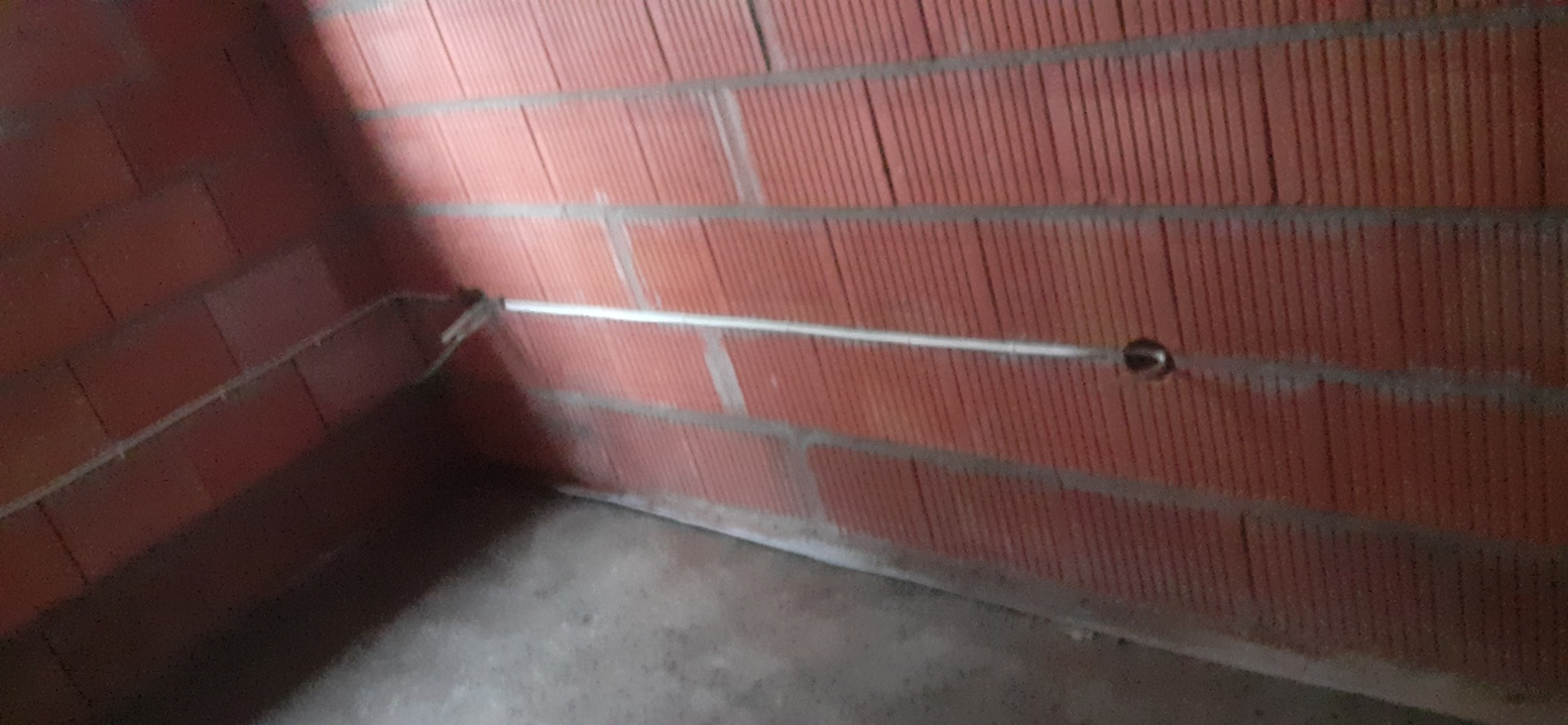 Wewnętrzna instalacja elektryczna w rurce PCV, zamontowana na ścianie z czerwonej cegły dziurawki. Widoczny otwór pod puszkę.