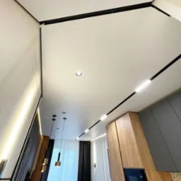 Nowoczesny, jasny sufit z oświetleniem liniowym i punktowym we Wrocławiu, widok z dołu, ukazujący minimalistyczny design wnętrza.