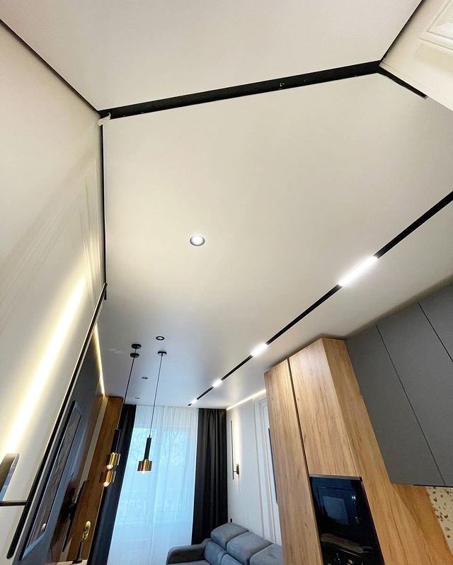 Nowoczesny, jasny sufit z oświetleniem liniowym i punktowym we Wrocławiu, widok z dołu, ukazujący minimalistyczny design wnętrza.