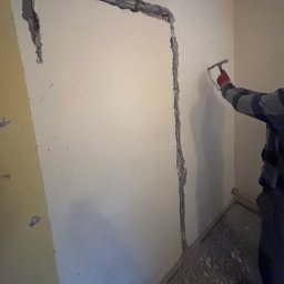 NFB INVEST SP. Z O.O. - Wykonywanie bruzdy pod instalację elektryczną w ścianie młotkiem w Szczecinie. Widoczny fragment ściany z wyżłobionym korytem.