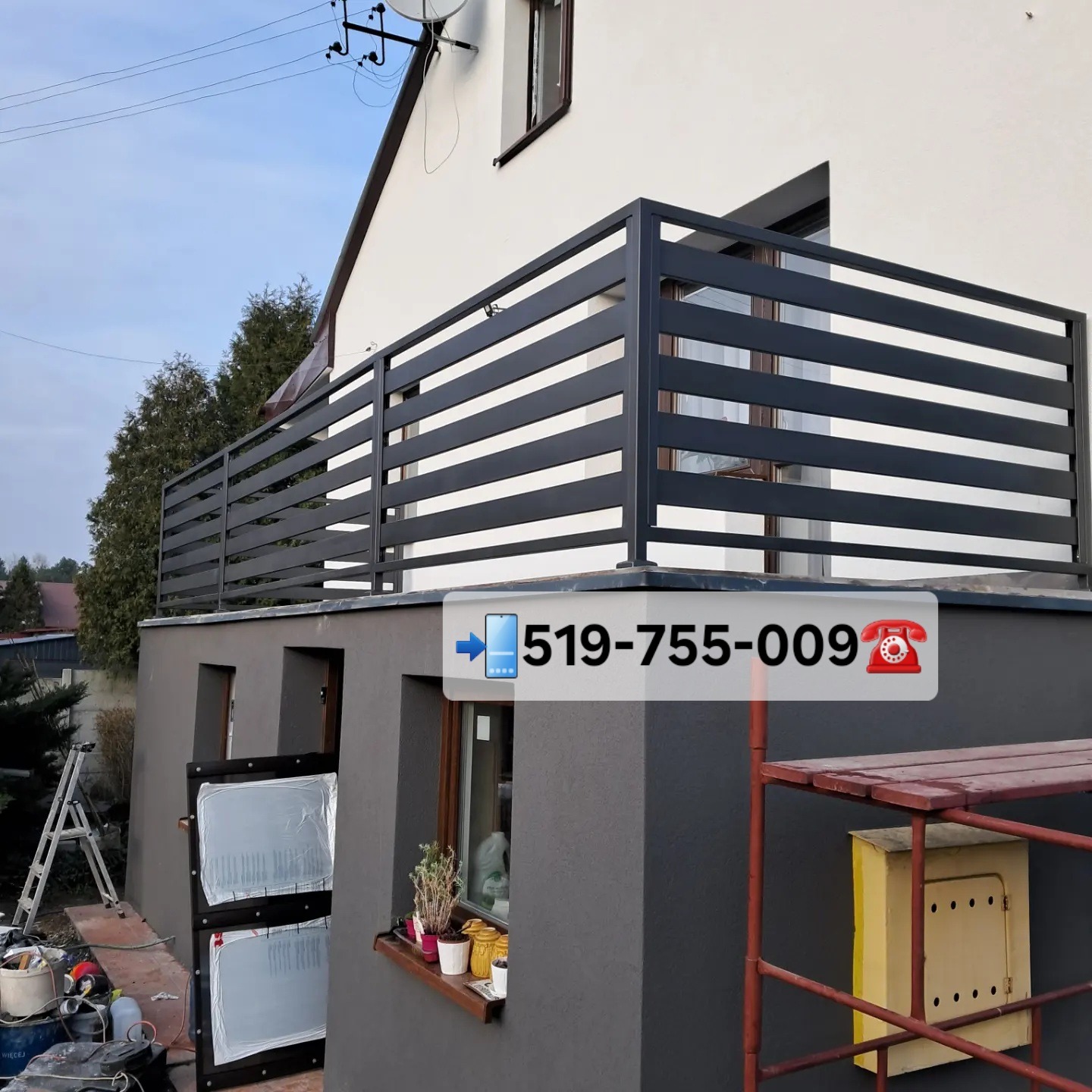 Nowoczesna, pozioma balustrada balkonowa w kolorze antracytowym, z widocznymi elementami montażowymi i fragmentem elewacji domu. Ujęcie z dołu, podkreślające minimalistyczny design.