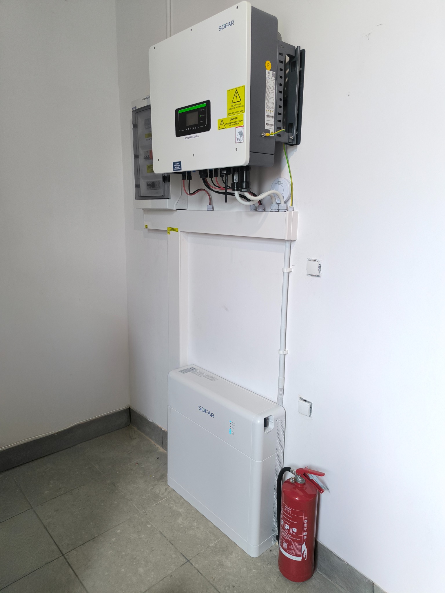 Instalacja fotowoltaiczna marki Sofar w pomieszczeniu w Pile, widoczny inwerter, rozdzielnica oraz zasobnik energii, obok gaśnica.