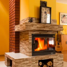 Nowoczesny kominek obłożony kamieniem dekoracyjnym z paleniskiem i zapasem drewna, ceglana kolumna po lewej, zegar i gitara w tle, żółta ściana.