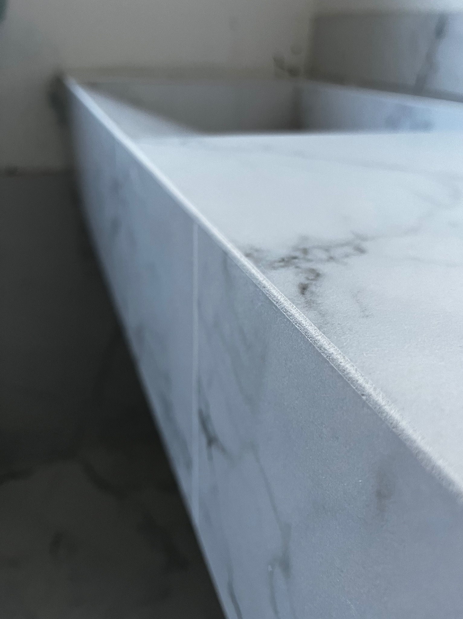 Fragment blatu umywalki z białego marmuru z widoczną fugą, zamontowany w łazience.