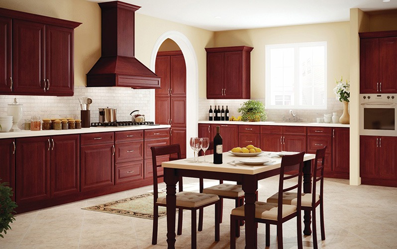 Kuchenne meble z ciemnego drewna, z blatem w kolorze złamanej bieli, uzupełnione o stół z krzesłami i dekoracyjne elementy, tworzą elegancką aranżację wnętrza.