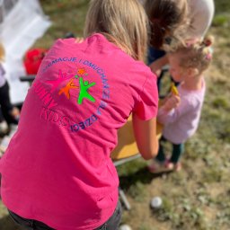 FUNNY KIDS Agnieszka Góra - Kobieta w różowej koszulce z napisem 'Animacje i Dmuchańce dla Dzieci Funny Kids' w otoczeniu dzieci, prawdopodobnie podczas organizacji imprezy plenerowej.