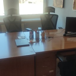 Fix.iT - Biuro z trzema krzesłami z siatkowym oparciem, biurkiem z drewnianym blatem, komputerem, laptopem i organizerami na długopisy, w tle szafka i tablica korkowa.