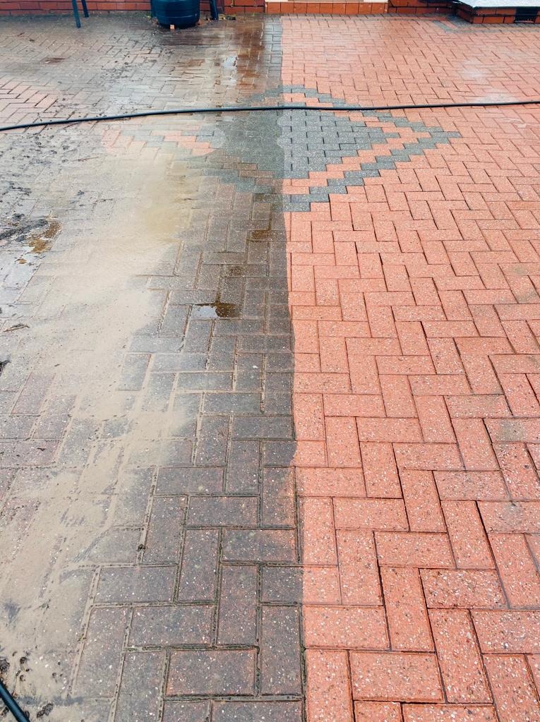 Częściowo wyczyszczona kostka brukowa w jodełkę, widoczna różnica między brudną, mokrą powierzchnią a czystą, suchą częścią.