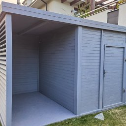 Paulina Witkowska - Szara, drewniana konstrukcja z lamelami i drzwiami, prawdopodobnie altana lub domek narzędziowy, na tle trawnika i domu.