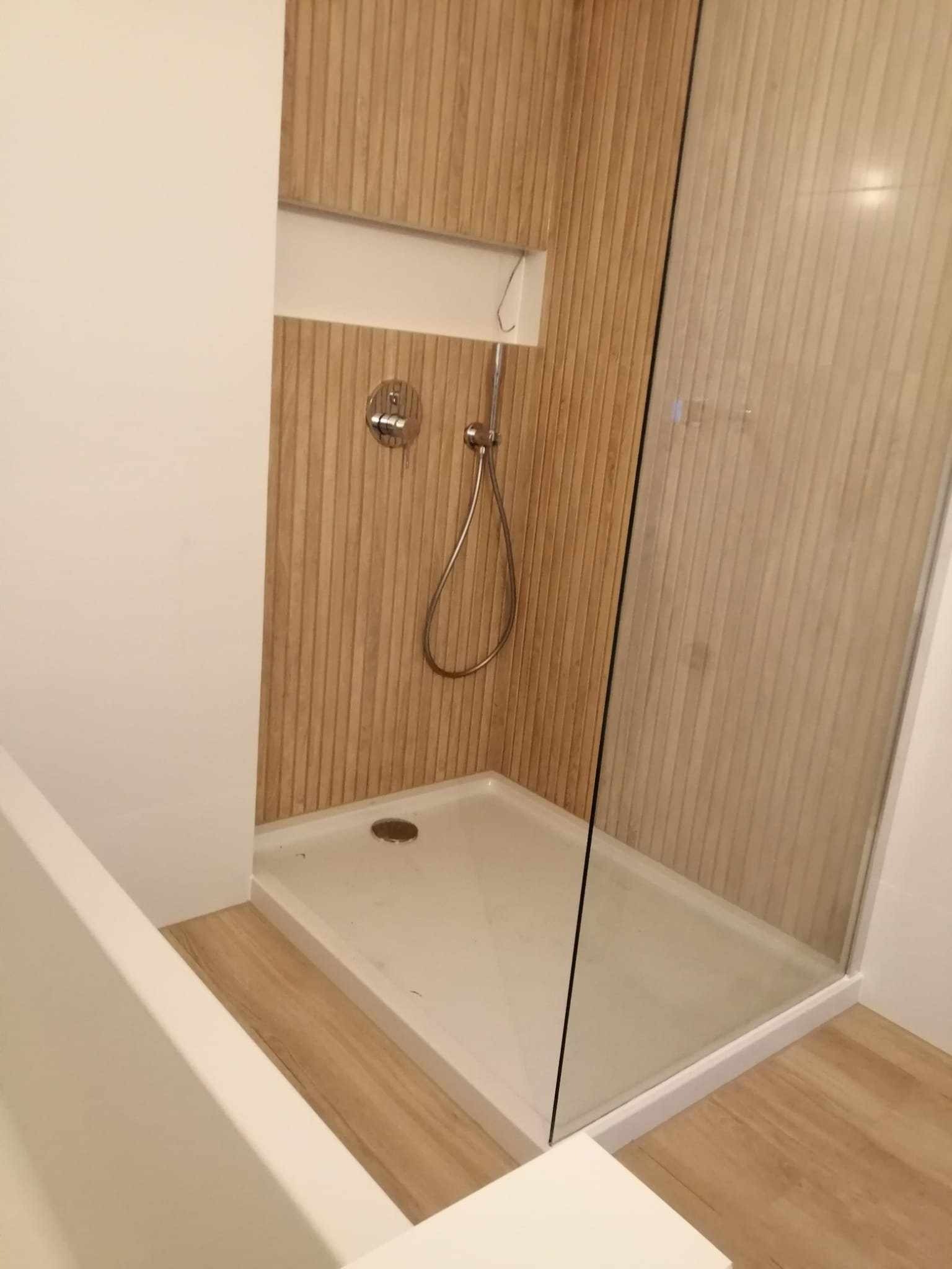 Nowoczesna kabina prysznicowa walk-in z odpływem liniowym, wykończona drewnopodobnymi panelami ściennymi w Gdańsku.