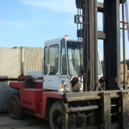 Wózek widłowy Kalmar LMV 12-1200 na tle jasnego nieba i stosu obrobionych bloków kamiennych.