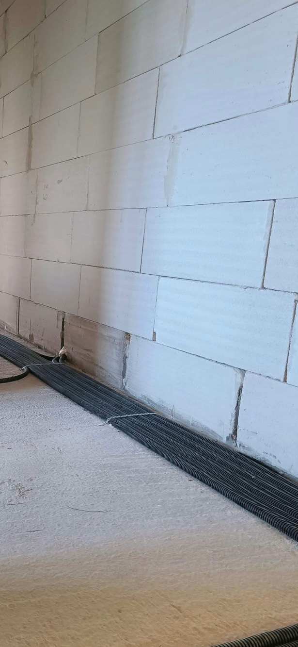 Rury instalacyjne w peszlu, ułożone przy ścianie z betonu komórkowego z wyciętymi bruzdami pod instalację.