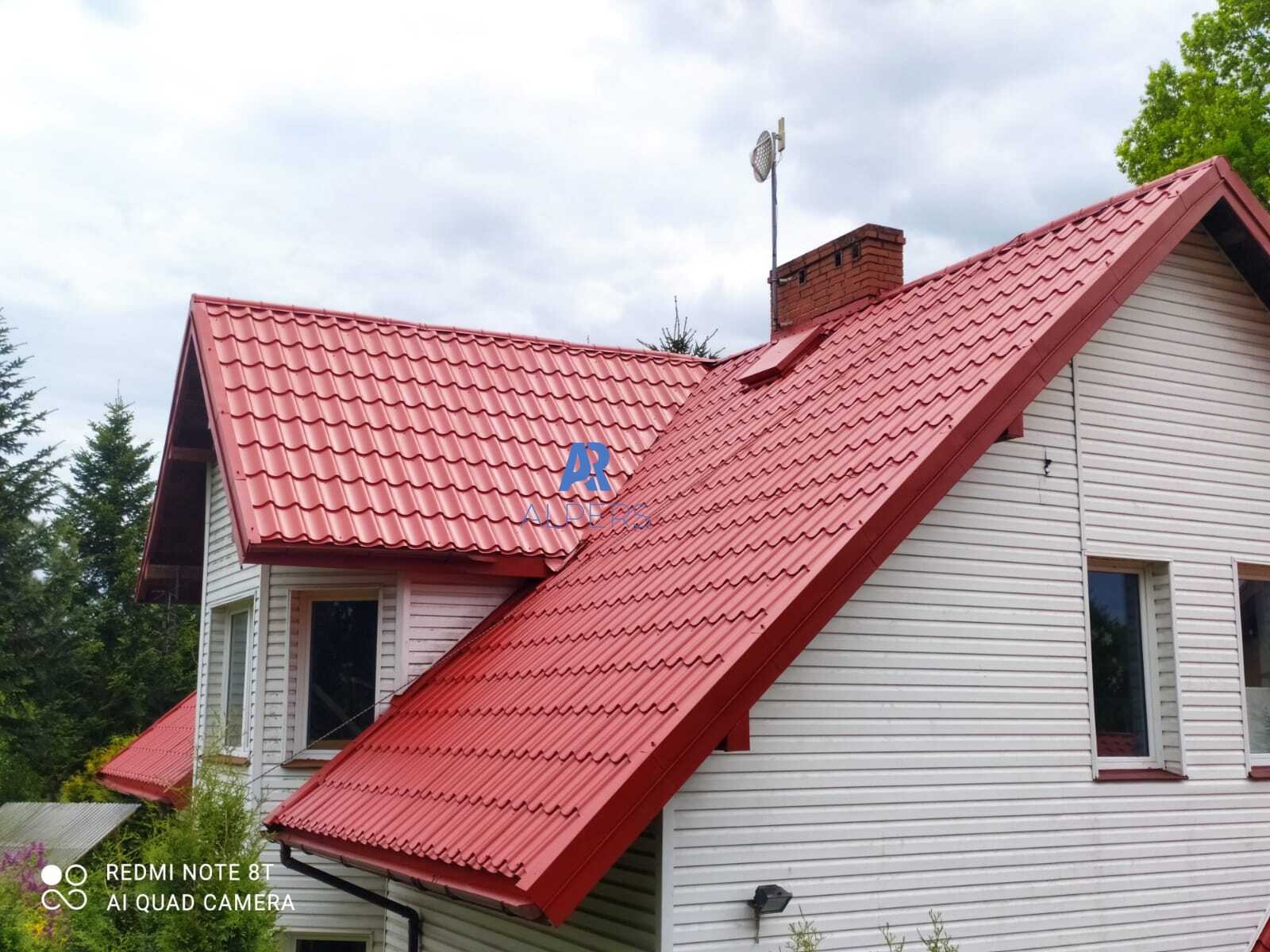 Dom jednorodzinny z nowym, czerwonym dachem z blachodachówki, widoczny komin i antena satelitarna, elewacja biała z sidingu.